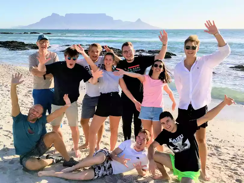 Tour group silhouettes catching sunset waves at Blouberg beach