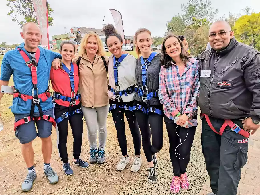 Excited group of travelers posing with the canyon bridge jump crew
