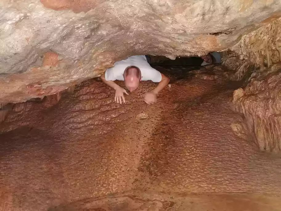 Wes navigating a tight crawl space inside the Cango Caves adventure path