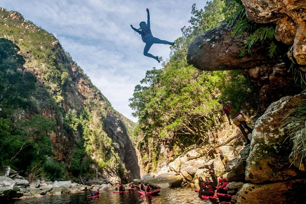 Adrenaline jumper jumping down from a cliff station into blue waters